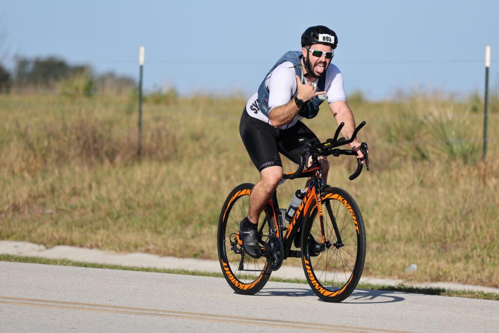 Me riding bike, while throwing a "shaka" sign with my right hand, in the Ironman 70.3.