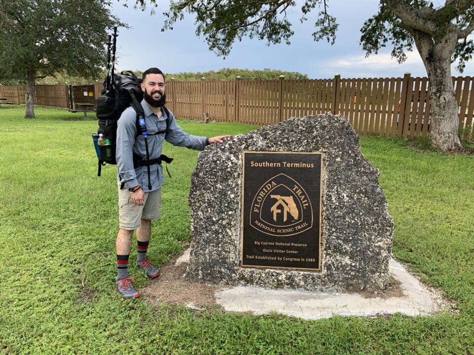 Alain next to the Southern Terminus signage for The Florida Trail.